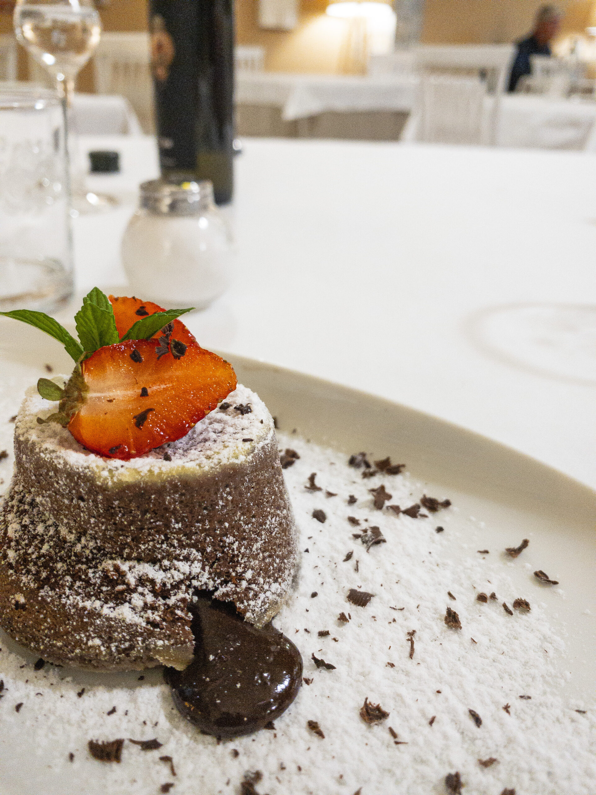 La tortina al cioccolato con il cuore caldo di cioccolato fondente, servita calda e decorata con fragole sarde e un foglietto di menta